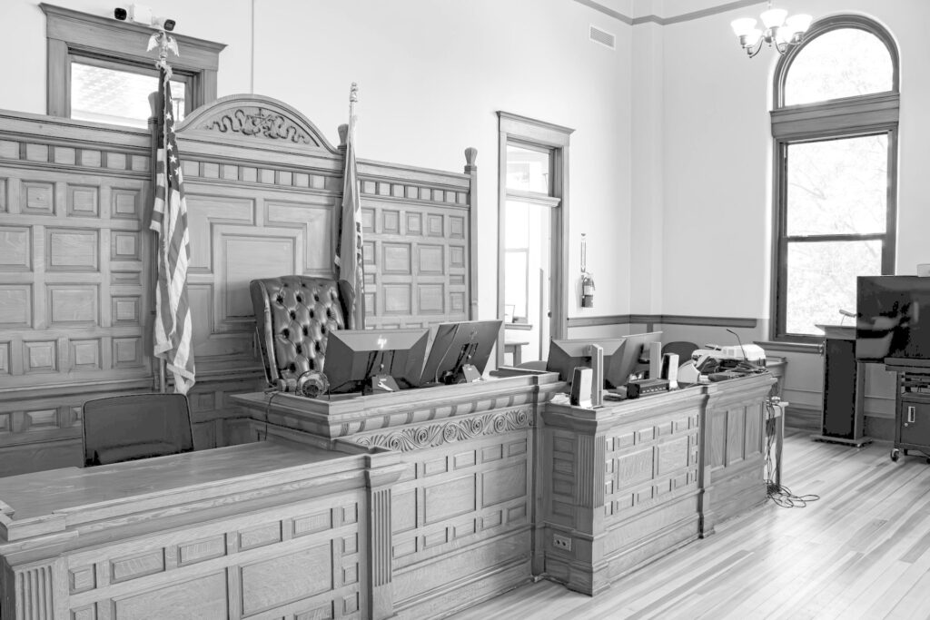 Empty American courtroom with the judge's bench and flags, in muted grey