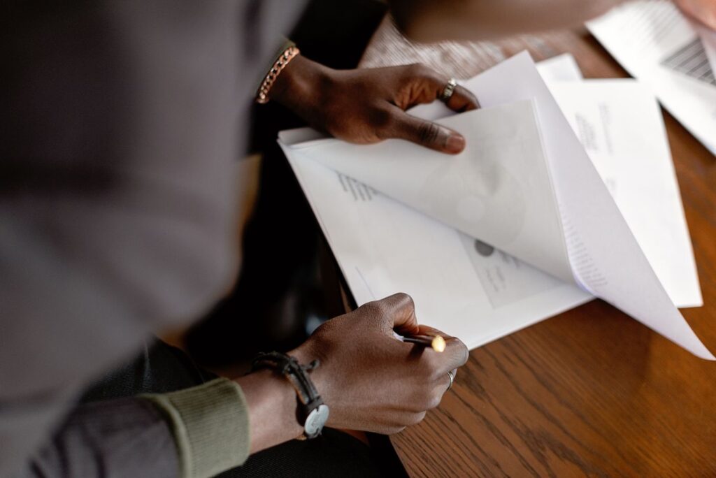 Close-up of a person calmly reviewing paperwork at a desk with a pen