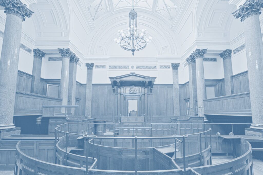 Historic courtroom with columns and a chandelier, tinted blue